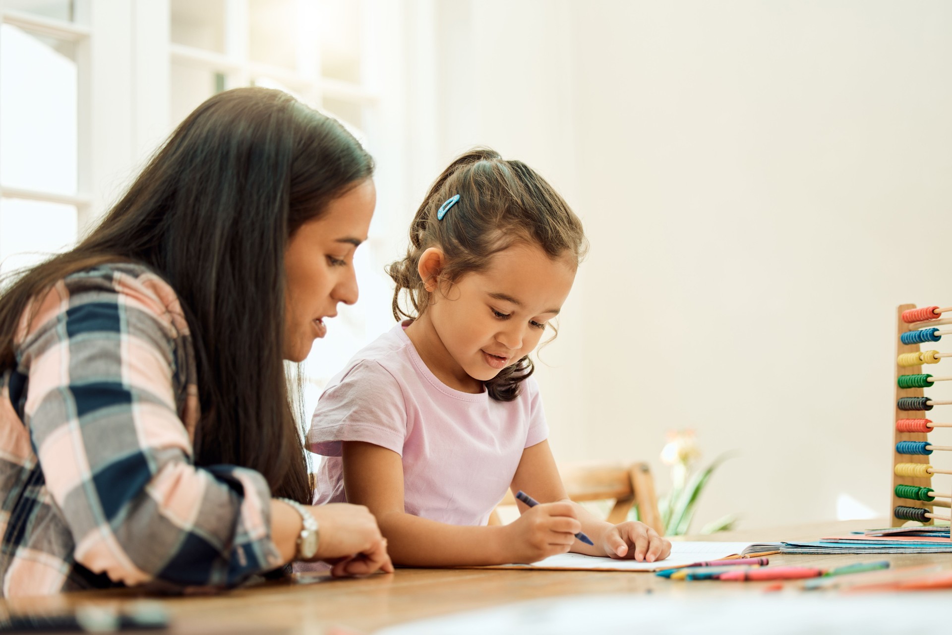Cropped shot of an adorable little girl doing her homework with some help from her mom